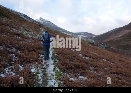 Einsame männliche fellwaker Klettern gefrorene Weg zur Wainwright Causey Pike im Nationalpark Lake District, Cumbria. de. Stockfoto