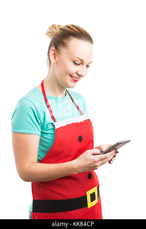 Glücklich lächelnde Hausfrau das Tragen der roten Weihnachten Schürze von SMS-Nachrichten oder Chatten auf dem Smartphone Handy Stockfoto