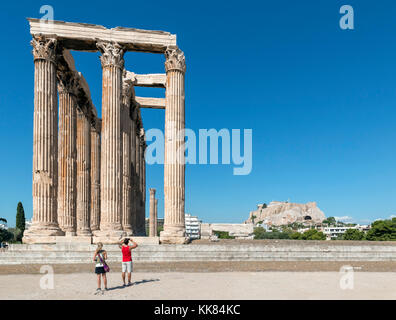 Paare, die sich vor dem Tempel des Olympischen Zeus (olympeion) mit der Akropolis im Hintergrund, Athen, Griechenland Stockfoto