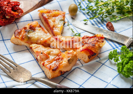 Runde Sausage Pizza Margarita in Stücke schneiden das Tuch mit Sun zu ernähren, getrockneten Tomaten. Selektive konzentrieren. Stockfoto