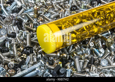 In der Nähe von Metall Schrauben in transparenter Box. Textur aus einem Haufen von kleinen silbrigen Schrauben. Technischer Hintergrund. Stahl Ersatzteile. Gelbes Kunststoffgehäuse. Stockfoto