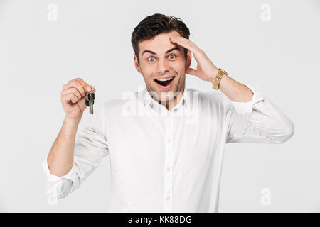 Portrait einer aufgeregt glücklich Mann mit Schlüssel, und wenn man die Kamera auf weißem Hintergrund Stockfoto