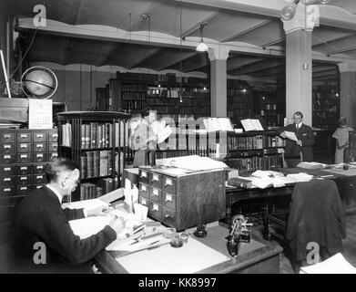 US Geological Survey Library im Hooe Gebäude, Washington DC. Hinweis drehbare Bücherregal auf der linken Seite, neben der Karte Kataloge, von Links nach Rechts: J.M. Wundt, J.L.V. McCord ursprünglichen Umfrage Bibliothekar, J.E. Latimer, und Maria Mäntel. Bild mit freundlicher Genehmigung durch USGS. 1917. Stockfoto