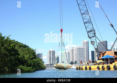 Response Crews heben ein Segelschiff aus der Biscayne Bay in Miami, 8. November 2017. Emergency Support Function 10 (ESF-10) Florida, die von der Environmental Protection Agency, Florida Fish and Wildlife Conservation Commission und der US-Küstenwache besteht, arbeitet mit Öl Spill Response Organisationen Schiffe zu entfernen, die beschädigt wurden und durch Hurrikan Irma verdrängt. Foto der US-Küstenwache vom Kleinoffizier der 2. Klasse Michael Himes. Stockfoto