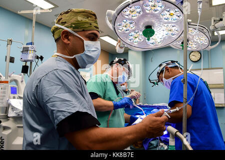 171108-N-PG 340-099 SAN JUAN, Puerto Rico (Nov. 8, 2017) Maj. Fernando Lopez Jr (links), aus dem 14 Combat Support Hospital (14 CSH), Kapitän Michael Carson, aus dem Militärischen Sealift Command Hospital Ship USNS Comfort (T-AH 20) und Maj. Marc Serra, aus der 14 CSH, Durchführen der Operation in einem Operationssaal an Bord des Schiffes. Komfort ist günstig pier Seite in San Juan, Puerto Rico, humanitäre Hilfe zur Verfügung zu stellen. Das Verteidigungsministerium ist die Unterstützung der Federal Emergency Management Agency, die federführende Bundesbehörde, dabei helfen, die Betroffenen durch den Hurrikan Maria Leiden zu minimieren und ist eine componen Stockfoto