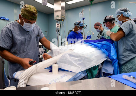 171108-N-PG 340-103 SAN JUAN, Puerto Rico (Nov. 8, 2017) Maj. Fernando Lopez Jr (links), aus dem 14 Combat Support Hospital (14 CSH), Maj. Marc Serra, aus der 14 CSH, Cmdr. Elliot Spencer, aus dem Militärischen Sealift Command Hospital Ship USNS Comfort (T-AH 20), Kapitän Michael Carson, von Komfort und Hospital Corpsman 3. Klasse Antonio Rangel von Komfort, Durchführen der Operation in einem Operationssaal an Bord des Schiffes. Komfort ist günstig pier Seite in San Juan, Puerto Rico, humanitäre Hilfe zur Verfügung zu stellen. Das Verteidigungsministerium ist die Unterstützung der Federal Emergency Management Agency, die Leitung des Bundes Stockfoto