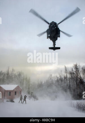 Alaska Air National Guard pararescuemen mit der 212Th Rescue Squadron mit einer eingehenden UH-60 Black Hawk Hubschrauber während einer Messe- und Unfallversicherung Schulungsveranstaltung an Joint Base Elmendorf-Richardson, Alaska, Nov. 21, 2017 kommunizieren. Während der Übung, die Rettung Betreiber befindet, bewertet, behandelt und zahlreiche Opfer evakuiert beim Einkuppeln und die Beseitigung mehrerer Angriffe von oppositionellen Kräften. Die Hubschrauber waren, die von den 1st Bataillon der Alaska Army National Guard, 207 Aviation Regiment. (U.S. Air Force Foto von Alejandro Peña) Stockfoto