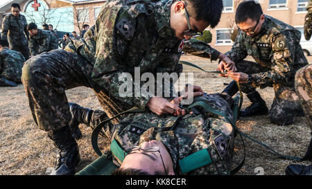 Soldaten zugeordnet 5. Republik Korea Armee Infanterie Division zeigt, wie man richtig ein Patient auf einen Wurf während ihrer Bekämpfung Life Savers Ausbildung bei Yeoncheon, Südkorea, Nov. 22, 2017. Die 210Th Field Artillery Brigade Mediziner durchgeführt eine erste Round Robin medizinische Ausbildung 5 ROKA-ID in das Verständnis der medizinischen Behandlung und die Bekämpfung der Bereitschaft zu helfen. (U.S. Armee Foto von Sgt. Michelle U. Blesam, 210Th FA BDE PAO) Stockfoto