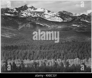 Schwarz-weiß Foto mit Blick auf die Bäume und die schneebedeckten Berge, mit Untertiteln "Long's Peak von der Straße, Rocky Mountain National Park', von Ansel Adams, von Fotografien von Nationalparks und Monumente, Colorado, United States, 1941. Stockfoto