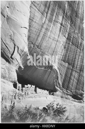 Ein schwarz-weiß Foto einer Siedlung am Fuße einer Klippe in Canyon de Chelly National Monument geschaffen, die Gegend ist eine der ältesten ununterbrochen bewohnten Gebiete in Nordamerika, es wird von den Navajo Tribal Vertrauen der Navajo Nation und wird in Zusammenarbeit mit dem National Park Service verwaltet, das Bild stammt aus einer Serie von Fotografien bekannt als das Wandbild Projekt von Ansel Adams, er durch den National Park Service 1941 beauftragt wurde, eine fotografische Wandbild für das Ministerium des Innern in Washington DC zu erstellen, wird das Projekt zu einem Ende kam wegen des Zweiten Weltkrieges, Stockfoto