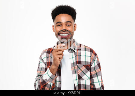 Porträt eines lustigen jungen afrikanischen Mann spielt mit Lupe auf weißem Hintergrund Stockfoto