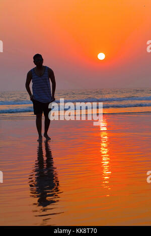 Junger Mann in Strandkleidung, der am Strand steht Stockfoto