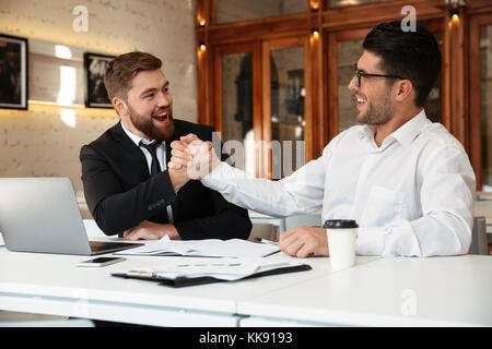 Zwei junge Schöne zufriedene Geschäftspartner in formale Hände schütteln im Büro Stockfoto