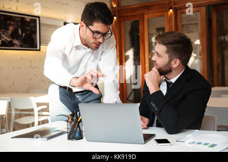 Unternehmer Unternehmensziele vor Notebooks am Arbeitsplatz im Büro besprechen Stockfoto