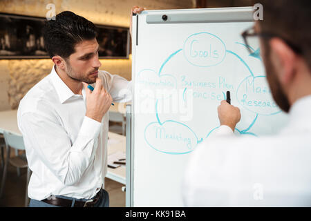 In der Nähe von zwei erfolgreichen Unternehmer in einer Besprechung und Diskussion von Plan auf einer Tafel im Innenbereich Stockfoto