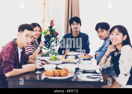 Abendessen mit asiatischen Gruppe von besten Freunden genießen Getränke am Abend während am Esstisch in der Küche sitzen zusammen, Soft Focus Stockfoto