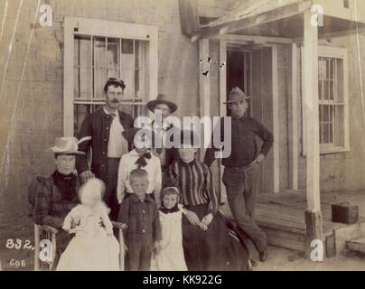 Schwarz-weiß Foto eines Soldaten, stehend auf der Rückseite, mit seiner Familie, zwei Männer, zwei Frauen und vier Kinder, einige Sitzen, Stehen, Draußen, vor einem Haus, 1905. Von der New York Public Library. Stockfoto