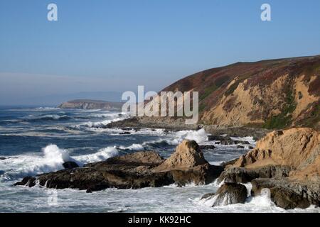 Ein Foto von Wellen gegen die Felsen, die Felsen, die ins Meer, die Wellen gegen sie zu brechen, eine Felswand beginnt in den Vordergrund und erstreckt sich in der Entfernung wo es einen Punkt, die weiter geht heraus in das Wasser, Bodega Bay, Kalifornien, 2014. Stockfoto