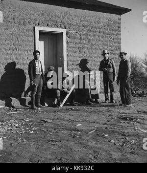 Schwarz-weiß Foto von einer Gruppe von Männern, die vor einem Gebäude stehen, mit der Überschrift "urveying Schleifring, WPA-Arbeiter, Bosque Farms Projekt", die von Dorothea Lange, amerikanischer Dokumentarfilm Fotograf und Fotojournalist, am besten für ihre Depression bekannt - Ära der Arbeit für die Farm Security Administration, Valencia, New York, 1935. Von der New York Public Library. Stockfoto