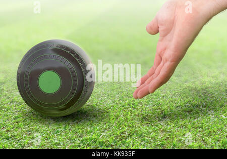 Eine männliche Hand Bowling und Freigeben einer Holz- Lawn Bowling Kugel auf einem grünen Rasen Gras Oberfläche-3D-render Stockfoto