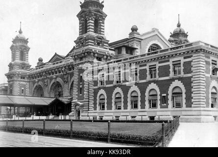 Ein Foto von einem Teil der Ellis Island Immigration Prüfplatz, der französischen Renaissance Revival Gebäude mit roten Ziegeln und Kalkstein Verkleidung konstruiert wird, das Gebäude wurde erstmals am 17. Dezember 1900 eröffnet, ist im Jahr 1954 war nach der Verarbeitung über 12 Millionen Einwanderer die Einreise in die Vereinigten Staaten geschlossen, Türme an den Ecken des zentralen Teil der Struktur mit einem überdachten Gang führt zum Haupteingang gesehen werden können, ein großes Grundstück von Gras wird durch eine kurze Zaun und Sträuchern geschützt, breite Gehwege umgeben das Gras und Gebäude, New York, 1907. Von der New York Public Stockfoto