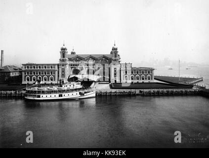 Eine äußere Foto des vorderen Fassade des Ellis Island Immigration Prüfplatz, der französischen Renaissance Revival Gebäude mit roten Ziegeln und Kalkstein Verkleidung konstruiert wird, das Gebäude wurde erstmals am 17. Dezember 1900 eröffnet, ist im Jahr 1954 war nach der Verarbeitung über 12 Millionen Einwanderer die Einreise in die Vereinigten Staaten geschlossen, Türme an den Ecken des zentralen Teil der Struktur mit einem überdachten Gang führt zum Haupteingang gesehen werden können, ein großes Boot ist am Ende des Laufstegs angedockt, New York, 1907. Von der New York Public Library. Stockfoto