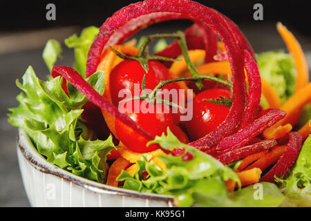 Salat mit roten Rüben, Karotten mit Spinat und Tomaten. dunklen Hintergrund. Fast Food im Sommer. ein Veganer Picknick Stockfoto