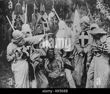 Schwarz-weiß Foto einer Gruppe von Klansmen umliegenden Freedman Gus (durch weiße Schauspieler Walter Lange in Blackface in einer Szene gespielt) von Direktor D W Griffith motion picture' Die Geburt einer Nation", 1915. Von der New York Public Library.