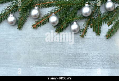 Silberfarbene Weihnachten Hintergrund mit Fichte Äste und kleine silberne Kugeln auf Holz Stockfoto