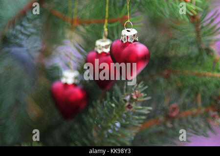 Drei rote Herzen hängen am Weihnachtsbaum Stockfoto