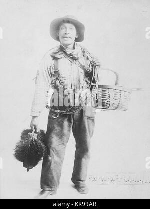 Sepia studio Portrait von einem Afrikaner Mann, volle Länge, volle Schornsteinfeger Kleidung, Holding einen Korb, Kabel und Kehrmaschinen, 1900. Von der New York Public Library. Stockfoto