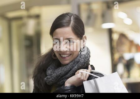 Porträt einer jungen Frau mit Einkaufstasche im Laden und lächelnd, Freiburg im Breisgau, Baden-Württemberg, Deutschland | Nutzung weltweit, gebührenfrei Stockfoto