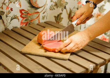 Frau schneiden frisches Lachsfilet auf Holzbrett Stockfoto