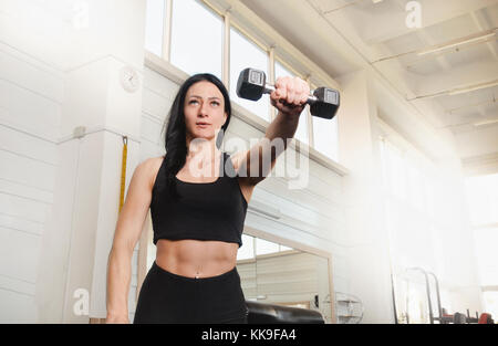 Glückliche junge fitness Frau trainieren. sport Frau Züge ihre Schultern mit Hanteln. Stockfoto