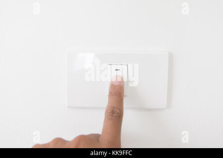 Closeup hand schalten Sie einen Netzschalter, Finger drücken Sie die Taste light, Hand mit Netzstecker, Innenraum electric power Button in Home, Konzept Licht einschalten Stockfoto