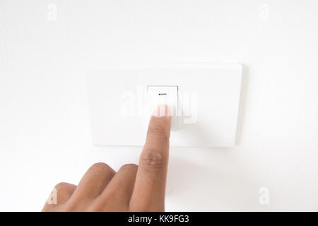 Closeup hand schalten Sie einen Netzschalter, Finger drücken Sie die Taste light, Hand mit Netzstecker, Innenraum electric power Button in Home, Konzept Licht einschalten Stockfoto