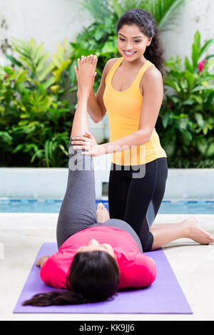 Junge Frau hilft ihrem Freund Bein in der richtigen Position in Bauchtraining zu erhöhen Stockfoto