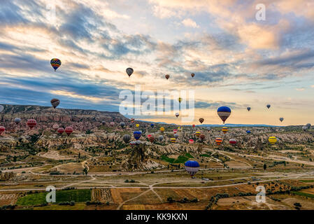 Familie der Feenkamine in Kappadokien bei bewölktem Himmel mit Heißluftballons in der Ferne, Göreme, Nevsehir, Türkei Stockfoto