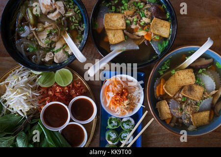 Traditionelle vietnamesische Küche. Suppen, Brötchen und frischen Kräutern. Platten auf einem Holz- Oberfläche. Stockfoto