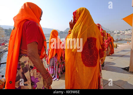 Indische Frauen in leuchtenden Saris an den ghats, Pushkar See, Rajasthan, Indien Stockfoto