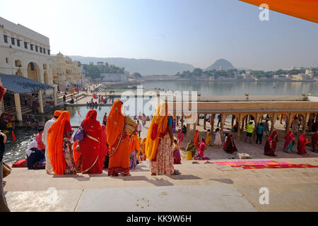 Indische Frauen in leuchtenden Saris an den ghats, Pushkar See, Rajasthan, Indien Stockfoto
