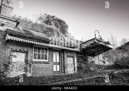 Schwarz-Weiß stilles viktorianisches Stationshaus in baufälliger Verfassung, das einer erheblichen Reparatur bedarf. Zugemauert, verlassen, verlassen, vergessen. Stockfoto