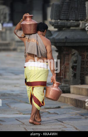 Morgen im Chenna Keshava Vishnu Tempel - Priester mit lota kalash Topf Opfergaben - Priester mit Kuferkrug beim Wasser holen Stockfoto