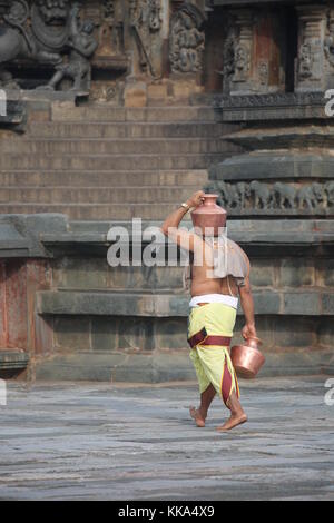 Morgen im Chenna Keshava Vishnu Tempel - Priester mit lota kalash Topf Opfergaben - Priester mit Kuferkrug beim Wasser holen Stockfoto