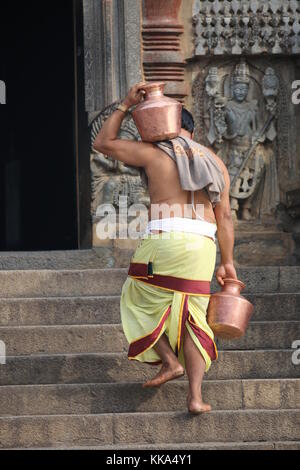 Morgen im Chenna Keshava Vishnu Tempel - Priester mit lota kalash Topf Opfergaben - Priester mit Kuferkrug beim Wasser holen Stockfoto