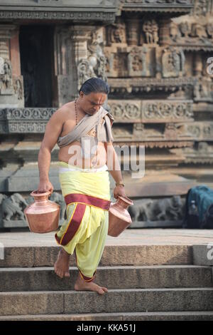 Morgen im Chenna Keshava Vishnu Tempel - Priester mit lota kalash Topf Opfergaben - Priester mit Kuferkrug beim Wasser holen Stockfoto