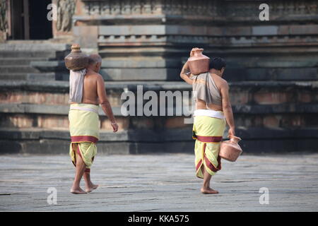 Morgen im Chenna Keshava Vishnu Tempel - Priester mit lota kalash Topf Opfergaben - Priester mit Kuferkrug beim Wasser holen Stockfoto