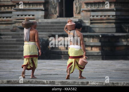 Morgen im Chenna Keshava Vishnu Tempel - Priester mit lota kalash Topf Opfergaben - Priester mit Kuferkrug beim Wasser holen Stockfoto