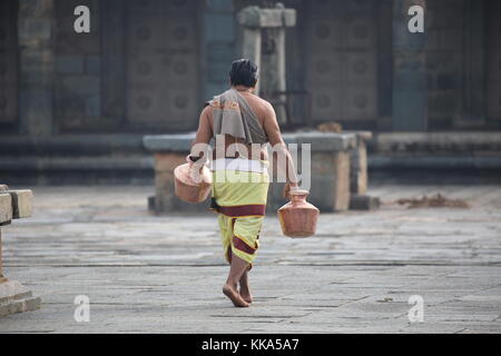 Morgen im Chenna Keshava Vishnu Tempel - Priester mit lota kalash Topf Opfergaben - Priester mit Kuferkrug beim Wasser holen Stockfoto