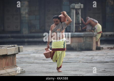 Morgen im Chenna Keshava Vishnu Tempel - Priester mit lota kalash Topf Opfergaben - Priester mit Kuferkrug beim Wasser holen Stockfoto